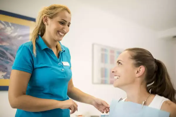 Zahnärztin im Gespräch mit lächelnder Patientin in moderner Zahnarztpraxis.