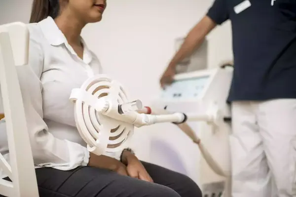 Frau erhält Magnetfeldtherapie am Arm in moderner Physiotherapie-Praxis.