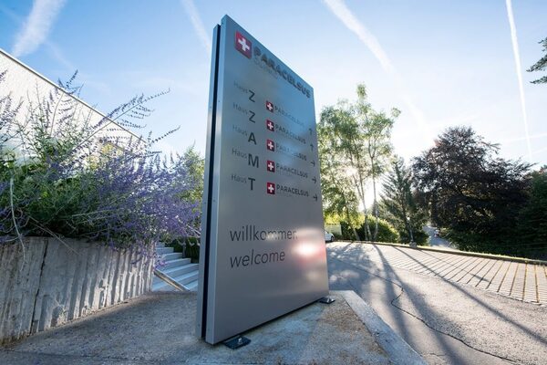 Beschilderung der Paracelsus Klinik im Freien mit Wegweisern und Begrüßungstext am Eingang.