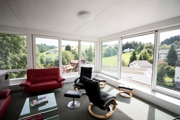 Helles Wohnzimmer mit Panoramafenstern, moderner Einrichtung und Blick ins Grüne.